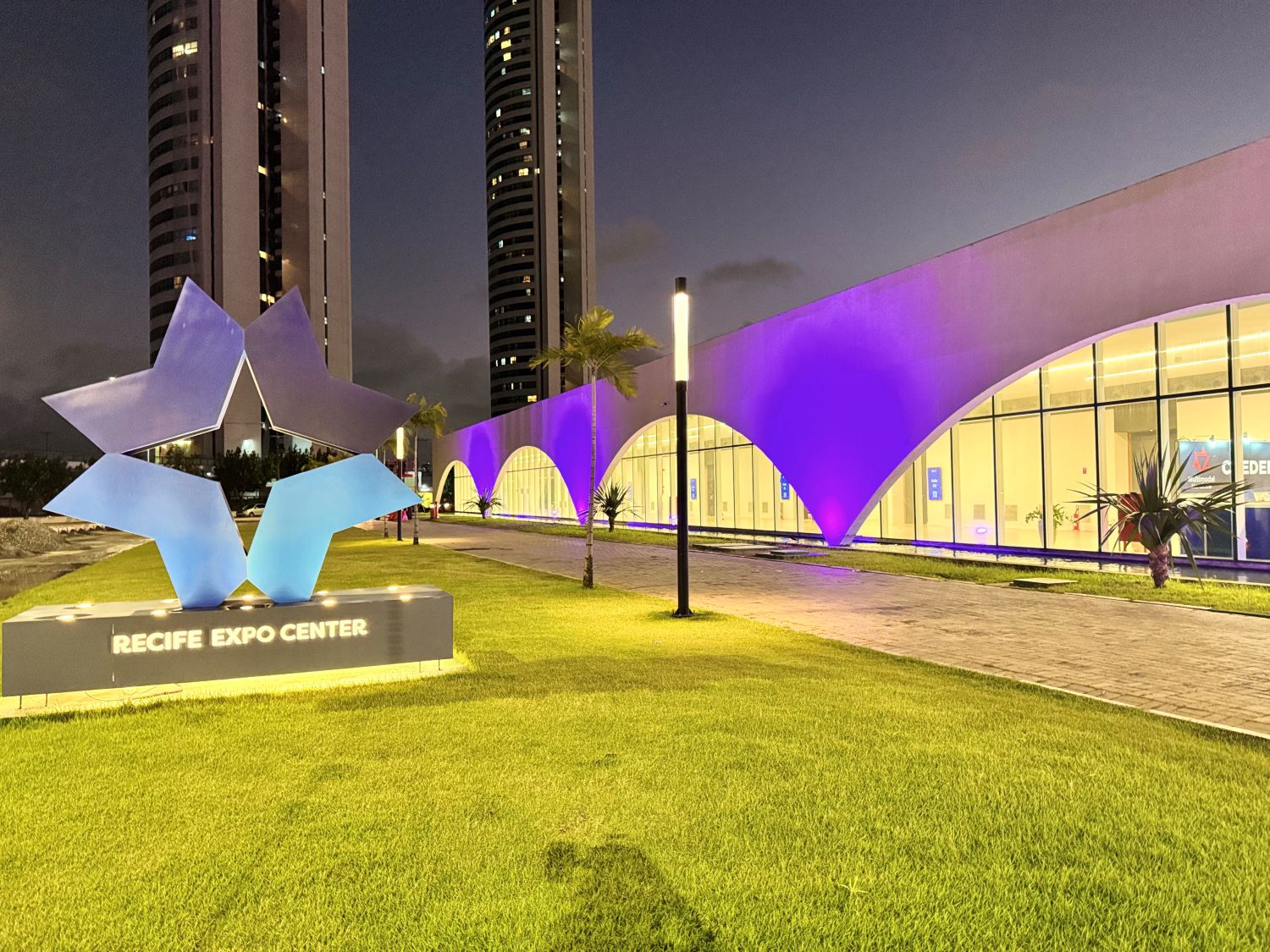 Foto da fachada do Recife Expo Center iluminada de roxo em prol da campanha de conscientização sobre o Alzheimer.